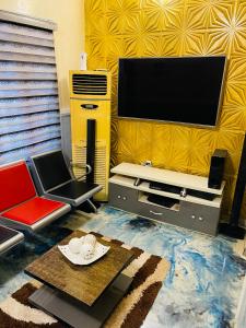 a living room with a flat screen tv and a table at Dsmarts apartments in Benin City