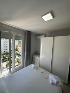 a bedroom with a white bed and a large window at Merville Apartment 6 in Durrës