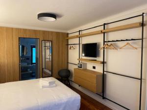 1 dormitorio con 1 cama y TV. en Hotel SALEI en Ghigo