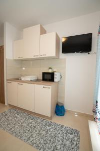 a kitchen with white cabinets and a microwave at Apartmani Vidušin in Novalja