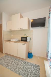 a kitchen with white cabinets and a microwave at Apartmani Vidušin in Novalja