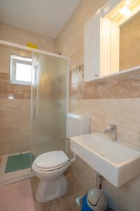 y baño con aseo, lavabo y ducha. en Apartmani Vidušin en Novalja