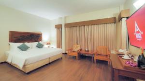 a hotel room with a bed and a tv and a desk at Siam Avari Hotel, Chiang Rai in Chiang Rai
