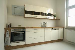 a kitchen with white cabinets and a tv on the wall at Apartment Mira in Senftenberg