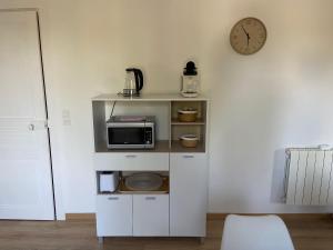a kitchen with a microwave and a clock on a wall at Maison La Vielmuroise in Vielmur-sur-Agout
