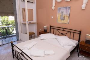 Schlafzimmer mit einem Bett mit weißer Bettwäsche und einem Balkon in der Unterkunft Drosia Studios - Λυμπερόπουλος in Pefki