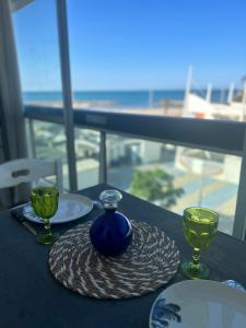 a table with a blue vase and two glasses on it at LA PLAGE in La Grande-Motte