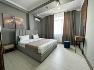 a bedroom with a bed and a desk in it at Lumarc Hotel in Bishkek