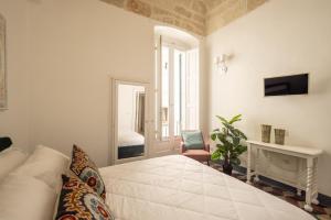 a white bedroom with a bed and a chair at Dimora Talenti City View in Polignano a Mare