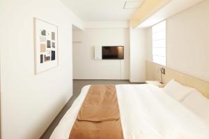 a bedroom with a bed and a tv on a wall at Shin-Osaka Station Hotel in Osaka