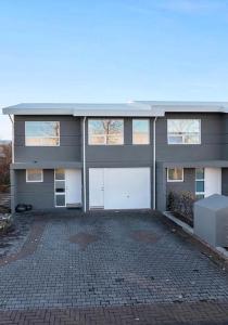 um grande edifício com duas portas de garagem numa entrada de tijolos em Family villa in suburban Reykjavik em Hafnarfjördur