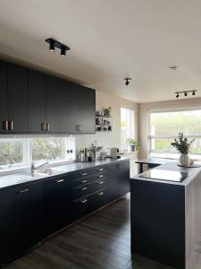 uma grande cozinha com armários pretos e uma grande janela em Family villa in suburban Reykjavik em Hafnarfjördur