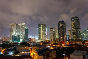 um horizonte da cidade à noite com edifícios altos em NEST NANO SUITES POBLACION-MAKATI em Manilla