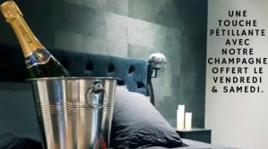 a bottle of champagne in a bucket next to a bed at Lorient Love Room Le King Size in Lorient