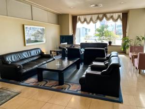 ein Wohnzimmer mit schwarzen Ledersofas und einem Tisch in der Unterkunft Ichihara Marine Hotel - Vacation STAY 01349v in Ichihara