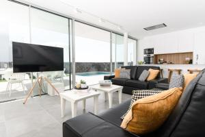 sala de estar con muebles de cuero negro y TV en Villa Moada Ocean Breeze en Callao Salvaje