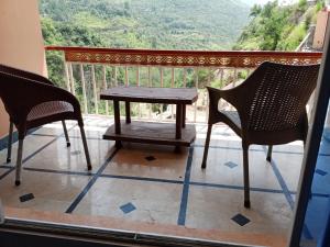 einen Tisch und zwei Stühle auf einem Balkon mit Aussicht in der Unterkunft Hotel Red Roof & Restaurant in Abbottābād