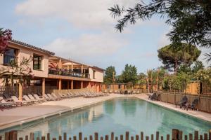 a swimming pool with chairs and a building at Blendin Retreat Agde in Le Grau-dʼAgde