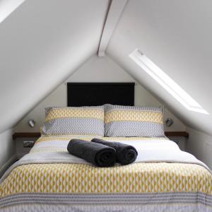 a bedroom with a bed with two black towels on it at The Bubble Hideaway - A Little Oasis near the Sea in Whitstable