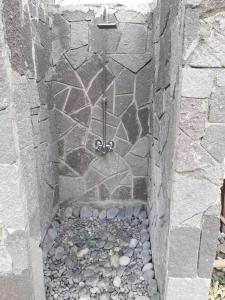 eine Dusche in einer Steinwand mit einem Kiesel in der Unterkunft Baranko Villa in Fort Portal