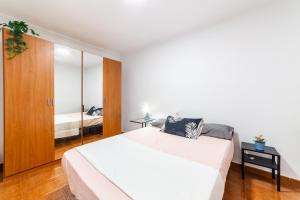1 dormitorio con 1 cama blanca grande y espejo en Casa Maruchi - Apartamento en Almería