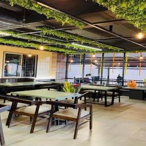 un restaurant avec des tables, des bancs et des plantes dans l'établissement Hotel Devgiri Inn and Restaurant, à Sāngli