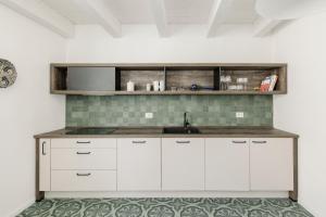 una cocina con armarios blancos y fregadero en AltaMarea - Ampi spazi in Centro storico en Carloforte