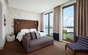 a bedroom with a bed and a chair and a large window at Sheraton Baku Intourist in Baku +37 photos