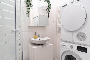 a white bathroom with a sink and a washing machine at Spacious Apartment, 3 min to U1 Reumannplatz in Vienna