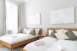 - 2 lits dans un dortoir blanc et vert dans l'établissement Spacious Apartment, 3 min to U1 Reumannplatz, à Vienne