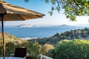 a patio with an umbrella and a view of the water at Messes Traditional Stone House with Amazing Sea View in Mandrakion