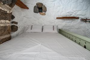 a bed in a room with a stone wall at Messes Traditional Stone House with Amazing Sea View in Mandrakion