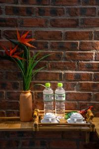 dos botellas de agua sentadas en una mesa junto a una pared de ladrillo en Hoi An Golden Bamboo An Bang Beach Villa & Spa en Hoi An