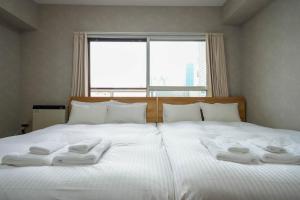 a bed with white towels on it with a window at Residence Hotel KABUTO in Sapporo
