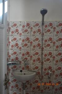 baño con lavabo y papel pintado con motivos florales en JOHN'S HOMESTAY, en Labuan Bajo