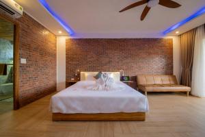 ein Schlafzimmer mit einem Bett und einer Ziegelwand in der Unterkunft Hoi An Golden Bamboo An Bang Beach Villa & Spa in Hoi An
