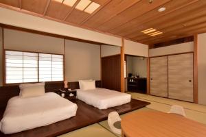 a bedroom with two beds and a table and chairs at Kawana Hotel in Ito