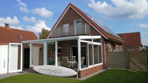 a house with a surfboard sitting in the yard at Ferienhaus Seekieker Timmel in Großefehn  +6 photos