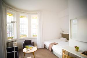 a bedroom with a bed and a table and windows at Hotel Haus Norderney in Norderney