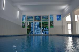a swimming pool with a fountain in a building at Pensiunea Maria Mihăești 