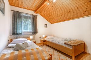 2 Betten in einem Zimmer mit Holzdecke in der Unterkunft House Mavko Near Lake Cerknica in Grahovo