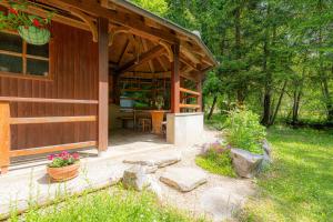 uma cabana de madeira com um alpendre e uma mesa em House Mavko Near Lake Cerknica em Grahovo