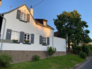 une maison blanche avec des fenêtres à volets noirs et un arbre dans l'établissement Scheunentraum Brenig, à Bornheim