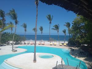 a swimming pool with palm trees and the ocean at White Elephant Sea Lodge in Malindi