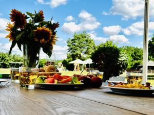 una mesa con un plato de fruta y un jarrón de flores en Julinek CAMP en Leszno