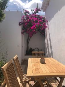 a wooden table and chairs on a patio with pink flowers at Casa Típica Ciutadella centro in Ciutadella