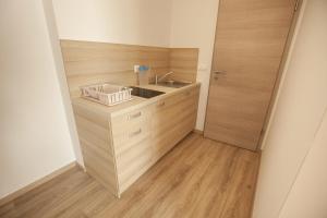 una pequeña cocina con fregadero y armarios de madera. en Sweet Dreams Rooms and Apartments Postojna, en Postojna