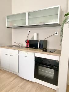 una cucina con armadi bianchi e forno nero di Appartement au coeur de Nice pour 4 - Clim & Wifi a Nizza