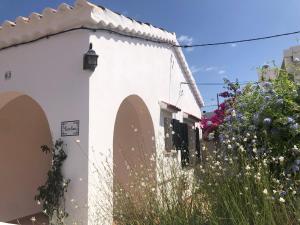 a white building with a fence and some flowers at Casa Típica Ciutadella centro in Ciutadella