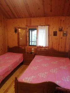 two beds in a wooden room with a window at Traditional Wooden Apartment in Koutsodímos